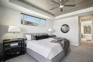 Carpeted bedroom with a raised ceiling, ceiling fan, and wooden ceiling