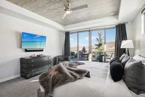 Bedroom with a tray ceiling, ceiling fan, and carpet floors