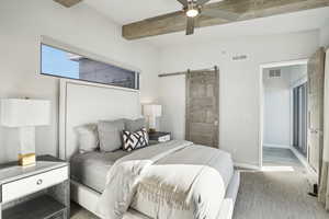 Bedroom featuring hardwood / wood-style floors, ceiling fan, a barn door, and beamed ceiling