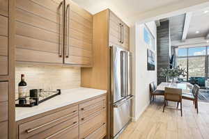 Kitchen featuring backsplash, high end fridge, light wood-type flooring, and beam ceiling