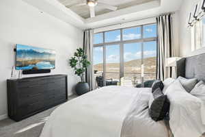 Carpeted bedroom featuring a mountain view, ceiling fan, access to exterior, and a tray ceiling