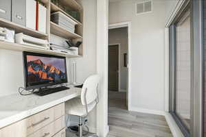 Office space featuring light hardwood / wood-style floors and built in desk