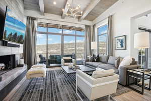 Living room with a tile fireplace, beam ceiling, hardwood / wood-style flooring, and a notable chandelier