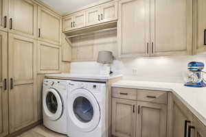 Laundry room with cabinets, light hardwood / wood-style floors, and washer and clothes dryer