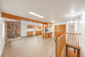 Interior space featuring a wood stove, a textured ceiling, brick wall, and light hardwood / wood-style flooring