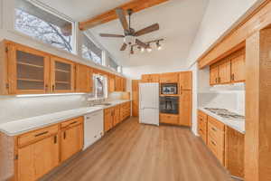 Kitchen with beam ceiling, ceiling fan, sink, light hardwood / wood-style floors, and white appliances