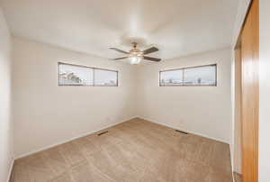 Spare room with light carpet, a wealth of natural light, and ceiling fan