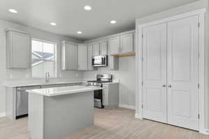 Kitchen with sink, a kitchen island, stainless steel appliances, and light hardwood / wood-style flooring