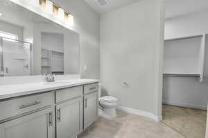 Bathroom featuring toilet, vanity, and a shower with shower door