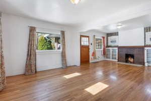 Unfurnished living room featuring a brick fireplace and light wood-type flooring