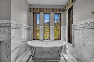 Bathroom featuring a wealth of natural light, a washtub, and tile walls