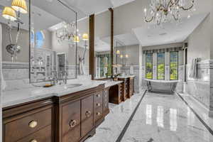 Bathroom with a bathing tub, vanity, a healthy amount of sunlight, and a high ceiling