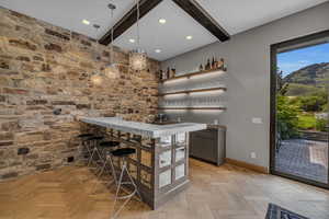 Bar featuring beamed ceiling, pendant lighting, and light parquet floors