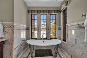 Bathroom with a washtub, a healthy amount of sunlight, and tile walls