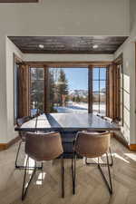 Dining area featuring a mountain view, wooden ceiling, light parquet floors, and a healthy amount of sunlight