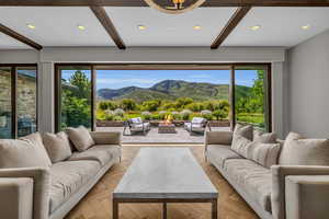 Living room with a mountain view, beam ceiling, an inviting chandelier, and light parquet floors