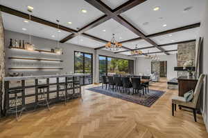 Dining room featuring beamed ceiling, a notable chandelier, bar, and light parquet flooring