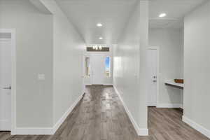 Hallway with light hardwood / wood-style floors and a chandelier