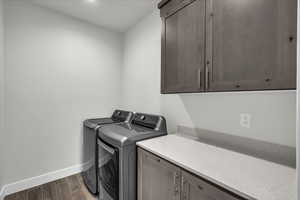 Laundry area with cabinets, independent washer and dryer, and dark wood-type flooring