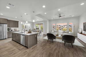 Kitchen with appliances with stainless steel finishes, sink, decorative light fixtures, a center island with sink, and hardwood / wood-style floors