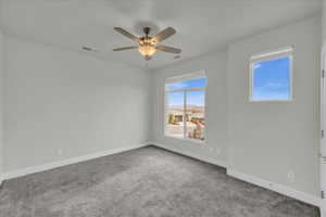 Carpeted empty room featuring ceiling fan