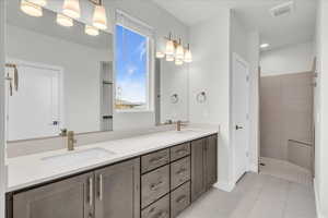 Bathroom with tile patterned flooring, vanity, and tiled shower