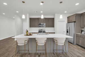 Kitchen with sink, stainless steel appliances, a center island with sink, and light hardwood / wood-style flooring