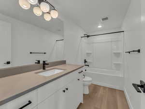 Bathroom with wood finished floors, visible vents, shower / bath combination, toilet, and vanity