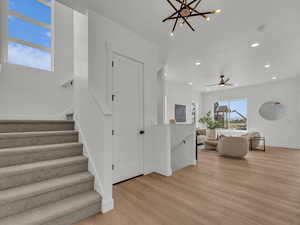 Interior space featuring ceiling fan with notable chandelier, baseboards, wood finished floors, and recessed lighting