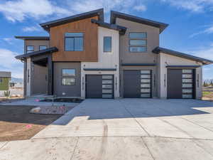 Contemporary home with a garage, stucco siding, and concrete driveway