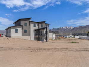 Rear view of property with stucco siding, a mountain view, a residential view, and a balcony
