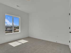 Carpeted spare room featuring visible vents and baseboards