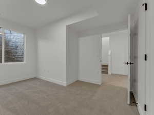 Spare room featuring light colored carpet and baseboards