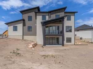 Rear view of property featuring stucco siding and a balcony