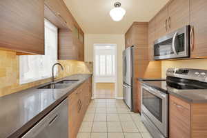 Kitchen featuring backsplash, sink, light tile patterned floors, and stainless steel appliances