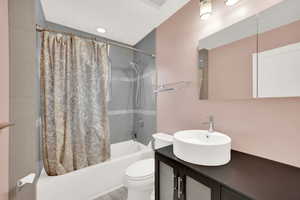 Full bathroom with vanity, toilet, and shower / bathtub combination with curtain