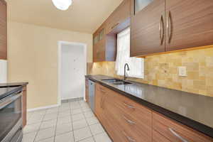 Kitchen with light tile patterned floors, stainless steel appliances, tasteful backsplash, and sink