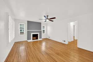 Unfurnished living room featuring ceiling fan, a wealth of natural light, and light hardwood / wood-style flooring