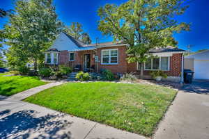 View of front of property with a front yard, an outbuilding, and a garage