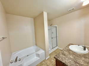 Bathroom with plus walk in shower, a textured ceiling, vanity, and tile patterned floors