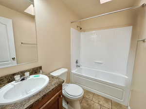 Full bathroom with vanity, bathing tub / shower combination, tile patterned floors, a skylight, and toilet