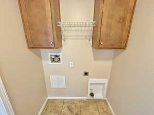 Washroom with cabinets, washer hookup, light tile patterned floors, and electric dryer hookup