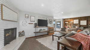 Living room featuring wooden walls, light colored carpet, a textured ceiling, and a brick fireplace