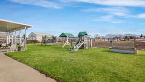 View of jungle gym with a mountain view, a trampoline, and a lawn