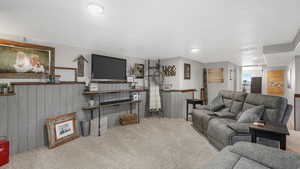 Living room featuring light colored carpet and wooden walls