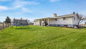 Rear view of house with a yard and a trampoline