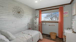 Bedroom featuring dark hardwood / wood-style flooring and wooden walls