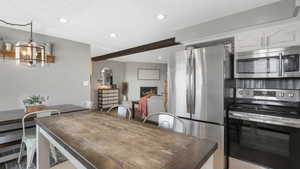 Dining space with a chandelier, a textured ceiling, a large fireplace, and beamed ceiling