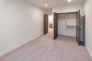 Unfurnished bedroom featuring light colored carpet and a closet