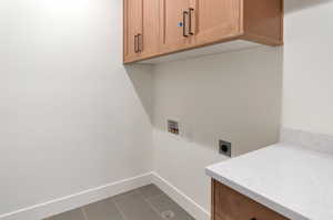 Laundry room featuring hookup for a washing machine, cabinets, dark tile patterned flooring, and hookup for an electric dryer